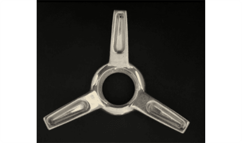 Three-pronged metallic object on a dark background.