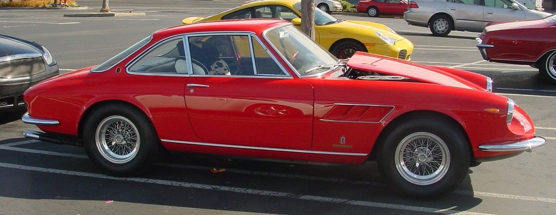 Red vintage sports car parked in lot.