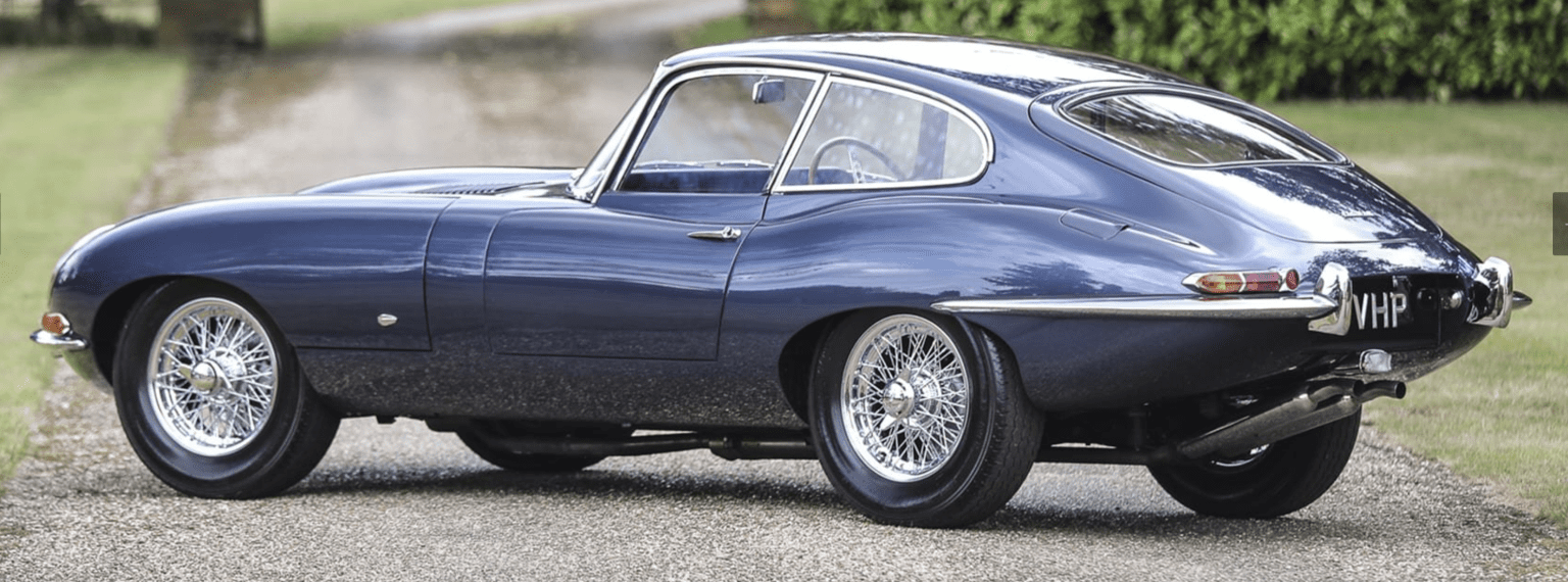 Classic blue sports car on gravel road.