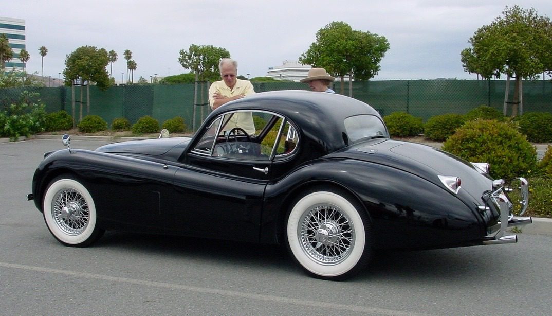 Vintage black car parked with two people.