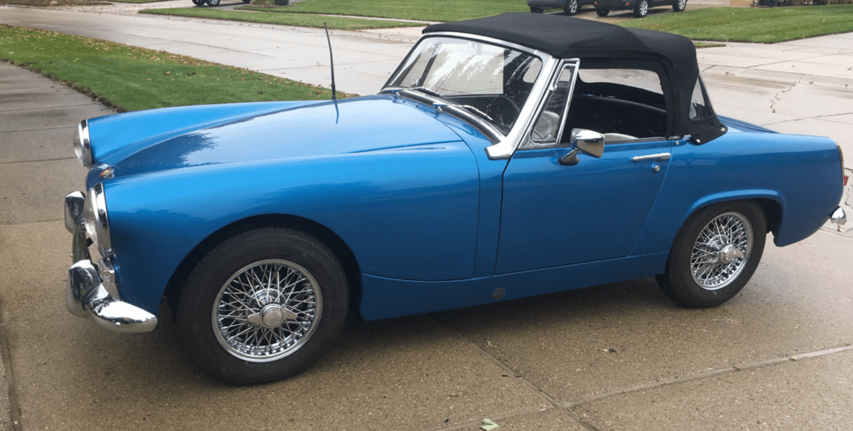 Blue vintage convertible car on wet pavement.