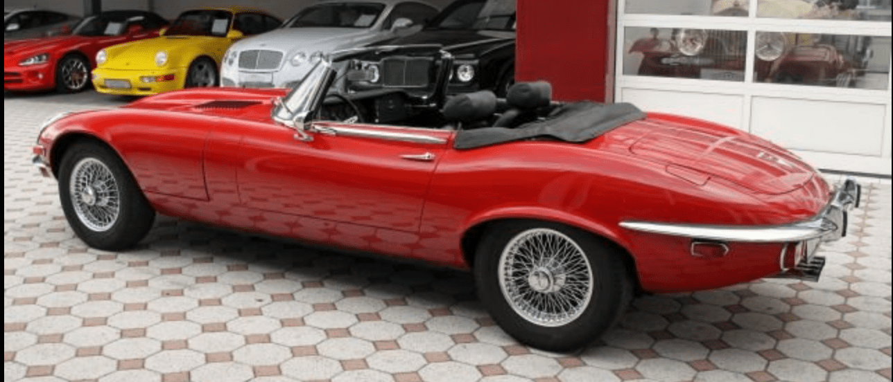 Red vintage convertible parked in a showroom.