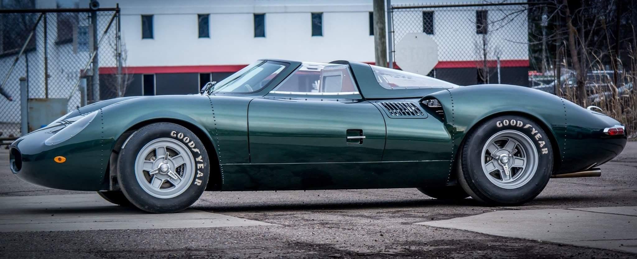 Green classic sports car parked on street.