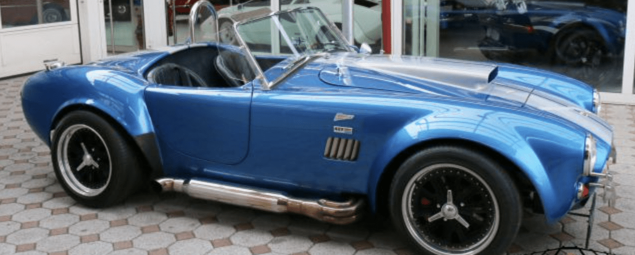 Blue vintage convertible sports car parked indoors.