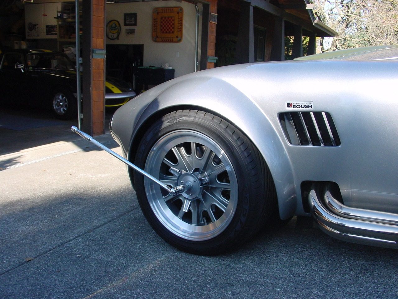 Silver car in garage with wheel alignment.