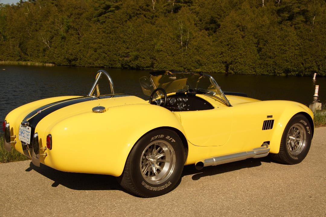 Yellow classic convertible parked near lake.