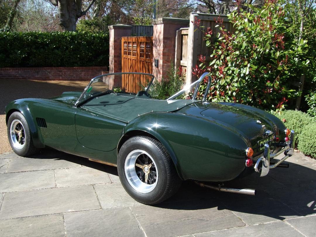 Green classic convertible car parked on pavement.