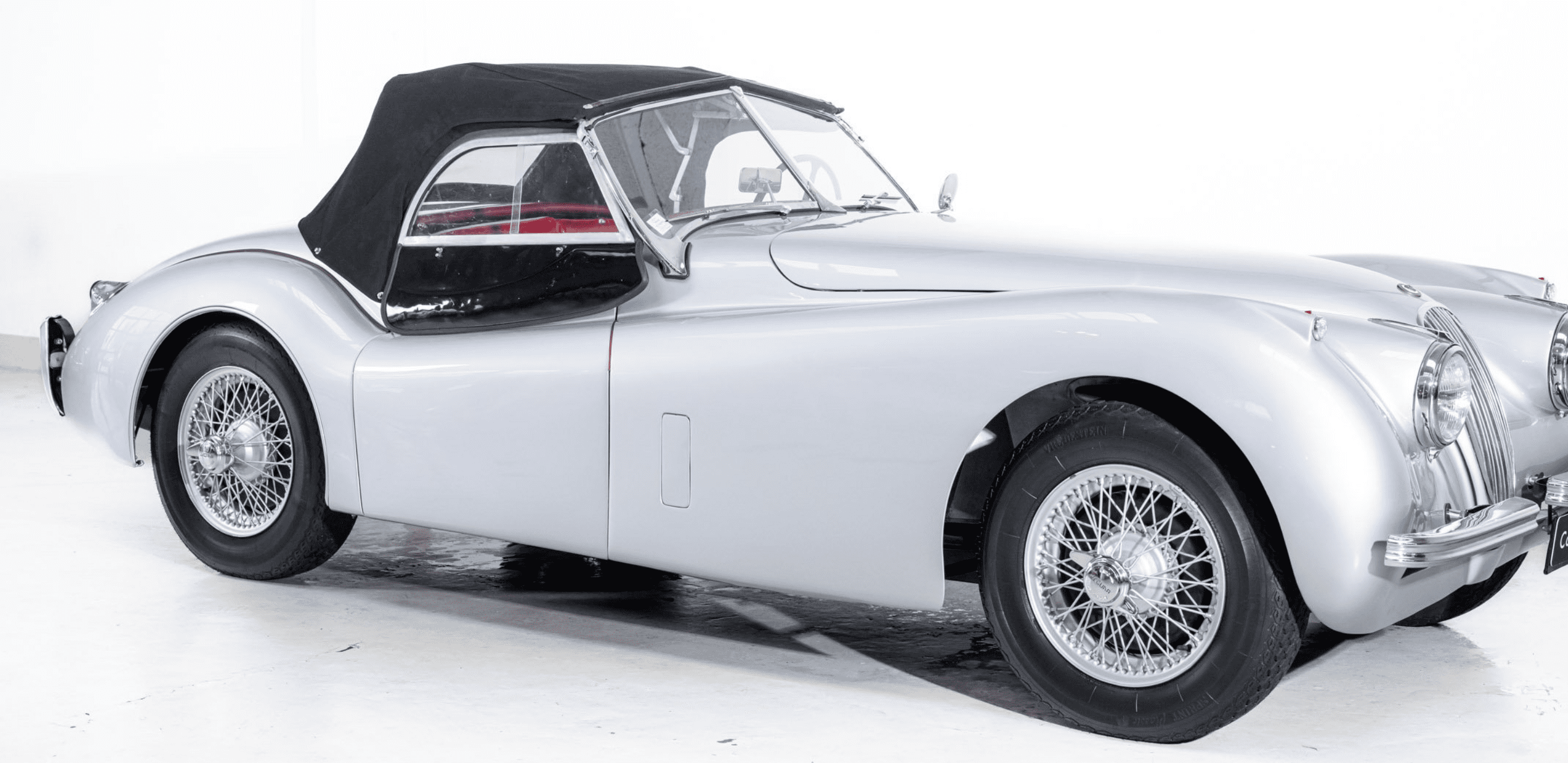 Classic silver convertible car with black roof.