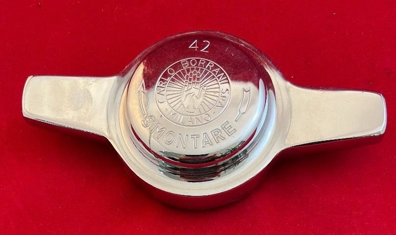 Chrome car wheel hub on red background.
