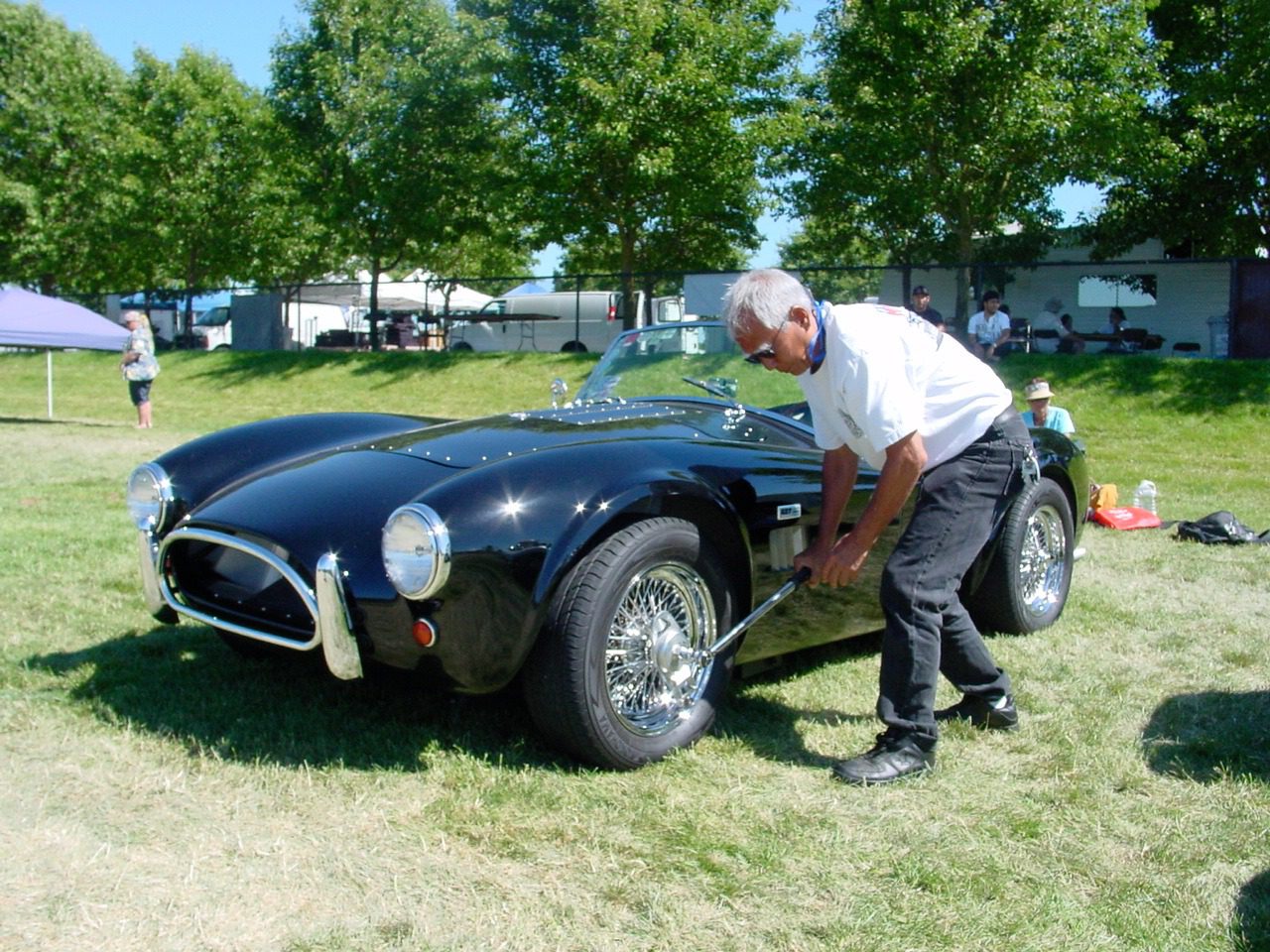 Man polishing classic black car outdoors.