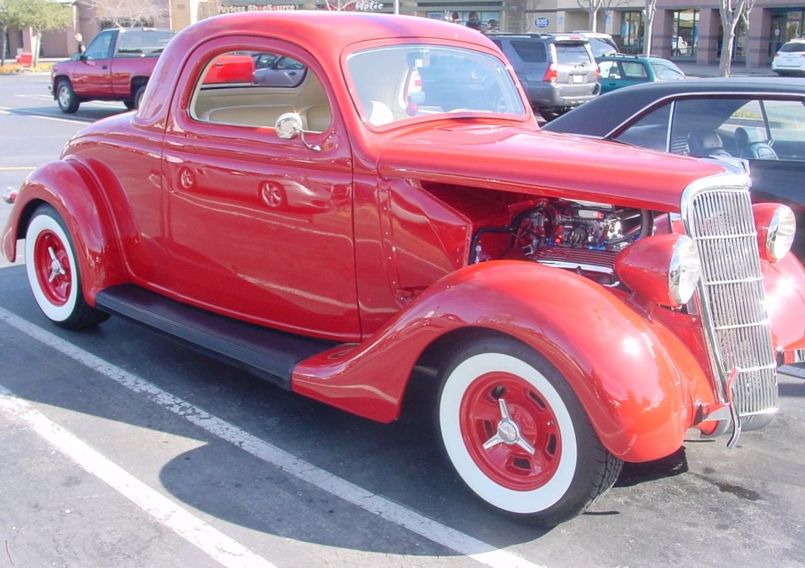 Red vintage car parked in a lot.
