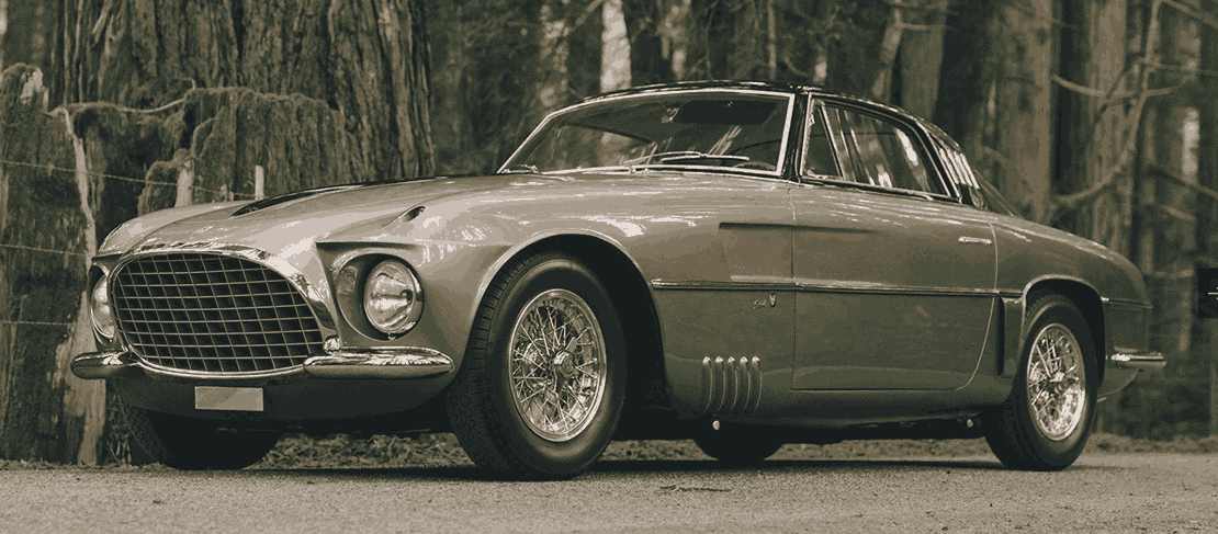 Vintage classic car parked in forest.