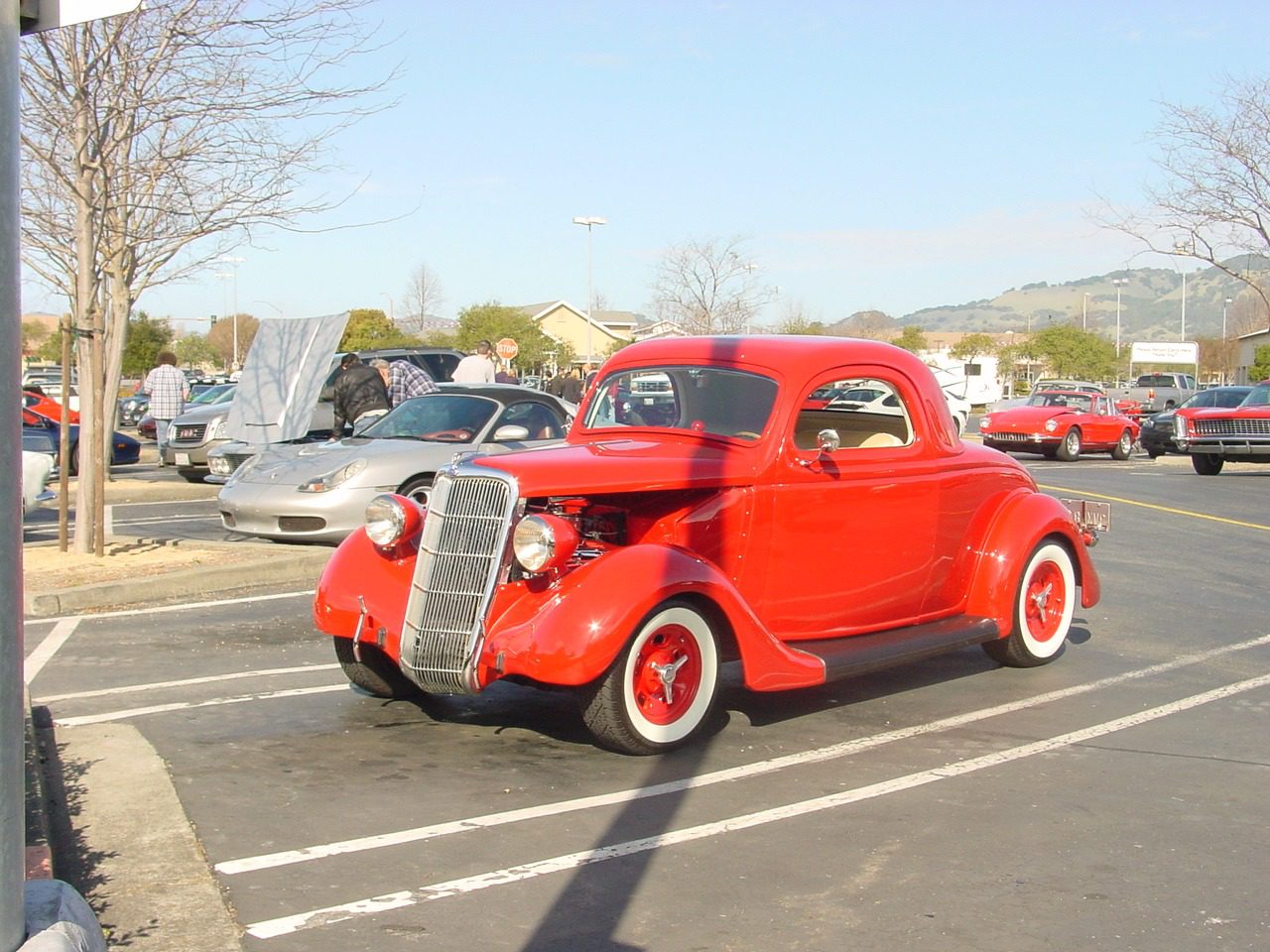 Red vintage car in parking lot.